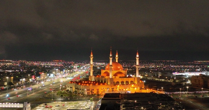 مسجد مضاء في حائل ليلاً تحت سماء غائمة، لقطة ليلية.