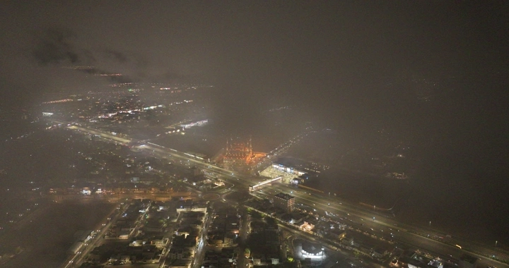 Hail city at night under clouds, aerial view.
