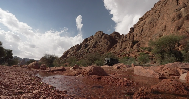 جبال حائل مع سيارة دفع رباعي في الوادي، لقطة واسعة.