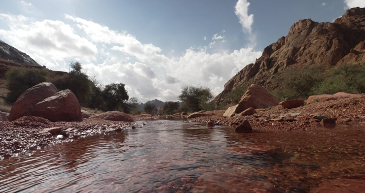 تيار مائي بين جبال حائل تحت سماء غائمة، لقطة منخفضة.