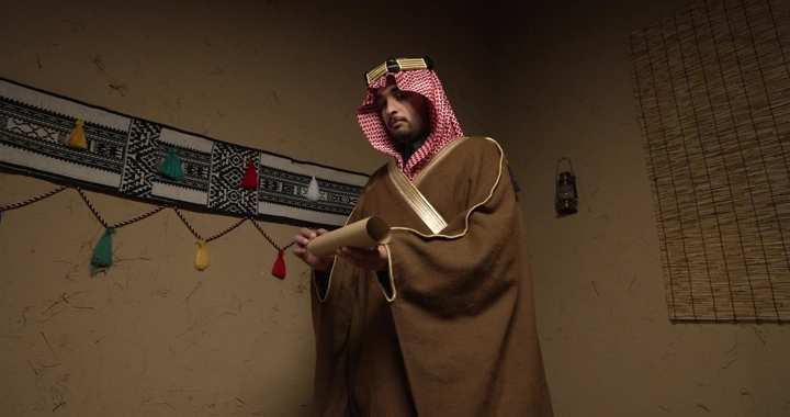 رجل يرتدي الزي التقليدي يفتح ورقة في غرفة تقليدية، لقطة داخلية.