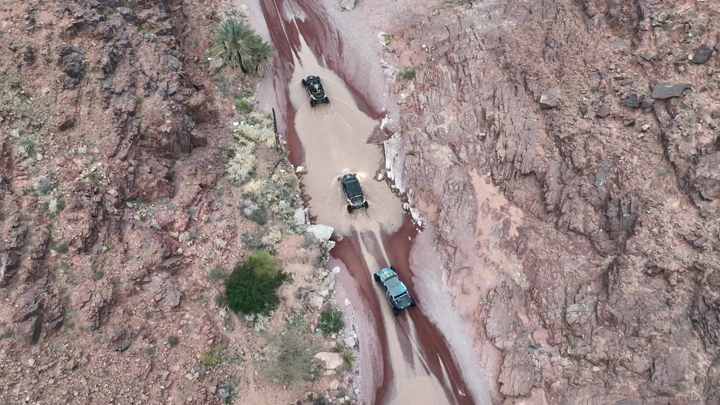 سيارات تسير في وادٍ جبلي بعد الأمطار، لقطة جوية.