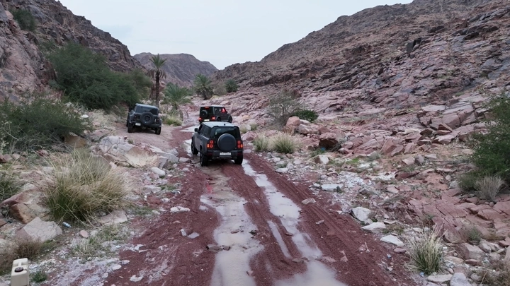 سيارات تسير في وادي جبلي بعد الأمطار، لقطة من الأرض.