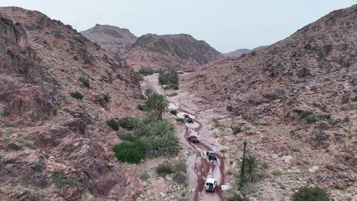سيارة تسير في وادٍ جبلي بعد الأمطار، لقطة جوية.