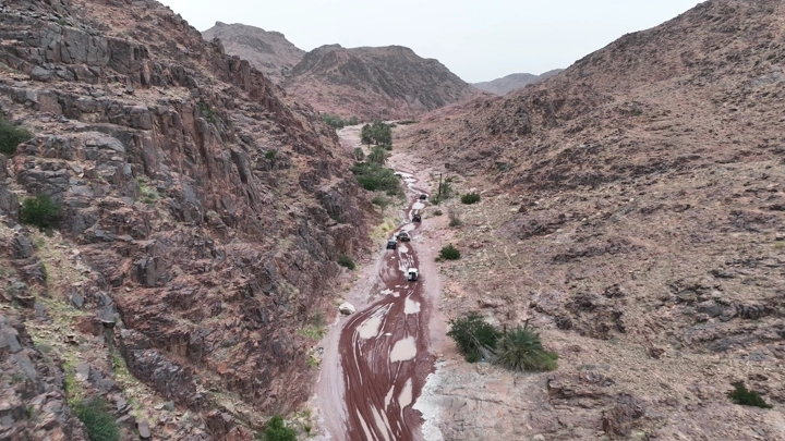 سيارة تسير بين جبال بعد الأمطار، لقطة جوية.
