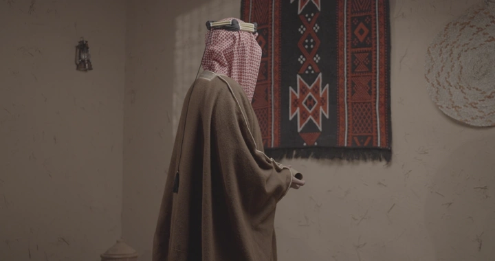 رجل سعودي يفتح ورقة في غرفة تقليدية، لقطة جانبية.