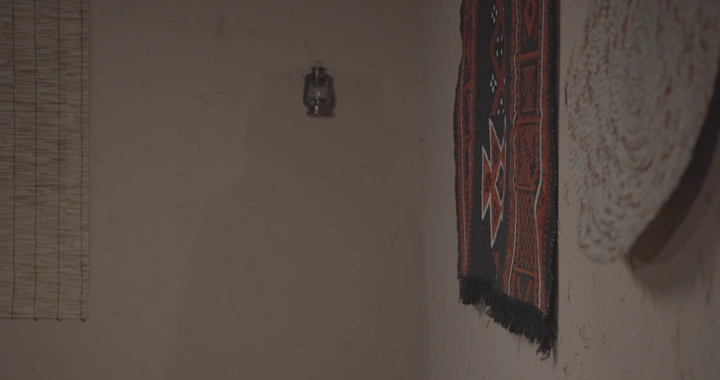 رجل يلمس سدو معلق على جدار في غرفة تقليدية، لقطة داخلية.