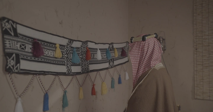 رجل سعودي يلمس سدو معلق على الحائط، تصوير داخلي.