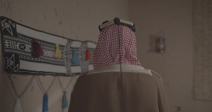 رجل سعودي يرتدي الزي التقليدي في غرفة مزينة، لقطة داخلية.