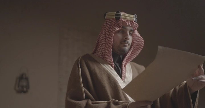 رجل سعودي يقرأ وثيقة في يوم التأسيس، لقطة داخلية.