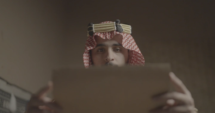 رجل سعودي يقرأ وثيقة في يوم التأسيس، لقطة قريبة.