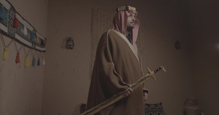 رجل سعودي يحمل سيفًا في غرفة تقليدية، لقطة داخلية.