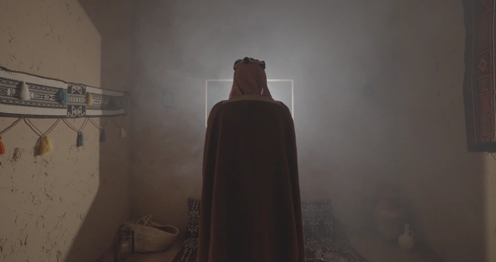 رجل سعودي يرتدي الزي يوم التاسيس في غرفة تراثية، لقطة داخلية.