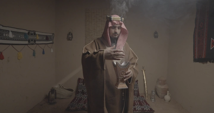 رجل سعودي يرتدي الزي التقليدي ويمسك مبخرة في غرفة تقليدية، لقطة داخلية.