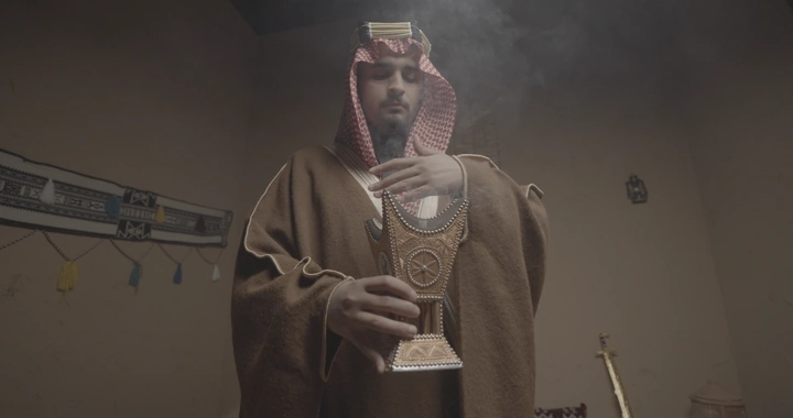 رجل سعودي يحمل مبخرة في غرفة تقليدية، لقطة داخلية.