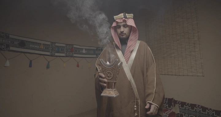 رجل سعودي يحمل مبخرة في غرفة تقليدية، لقطة داخلية.