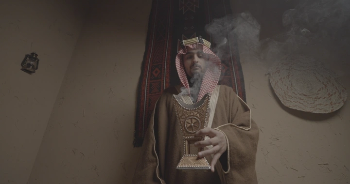 رجل سعودي يحمل مبخرة في غرفة تقليدية، لقطة داخلية.