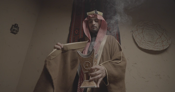 رجل سعودي يحمل مبخرة في غرفة تقليدية، لقطة داخلية.