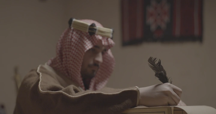 رجل سعودي يكتب بريشة في يوم التأسيس، لقطة داخلية.