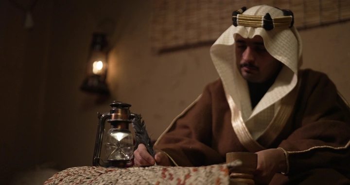 رجل سعودي يكتب في يوم التأسيس، إضاءة خافتة، لقطة داخلية.