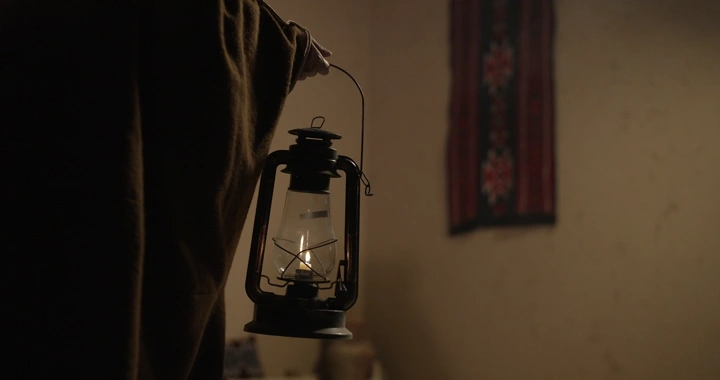 رجل يحمل فانوسًا في غرفة تقليدية، لقطة داخلية.