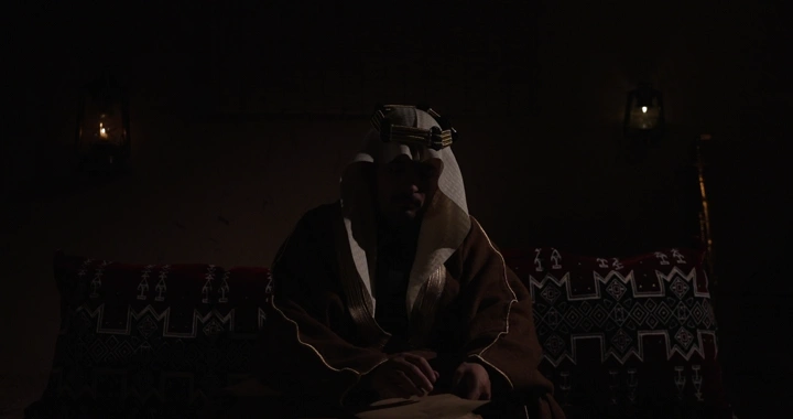 رجل سعودي يقرأ في يوم التأسيس، إضاءة خافتة.