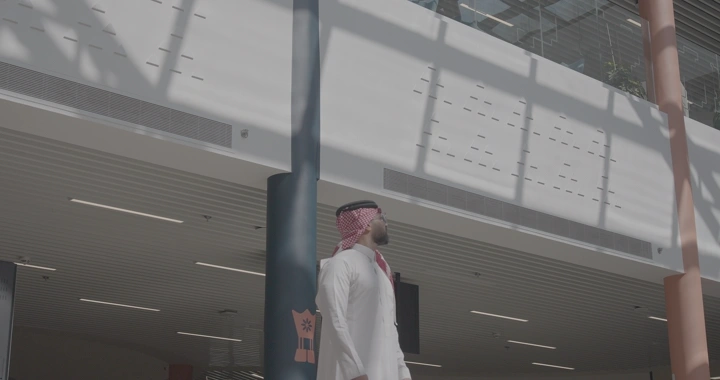 رجل بزي سعودي تحت أشعة الشمس في مبنى حديث، لقطة جانبية.