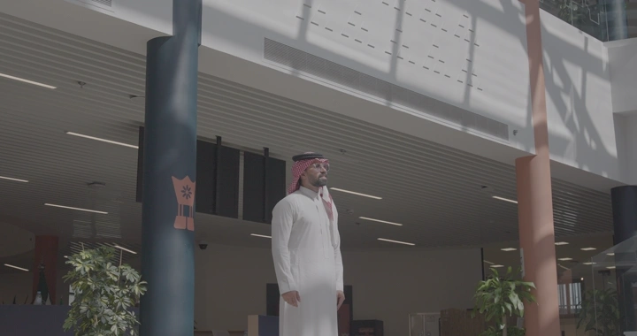 رجل بزي سعودي تحت أشعة الشمس في مبنى حديث، لقطة واسعة.