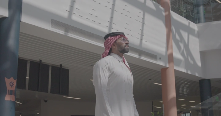 رجل بزي سعودي تحت أشعة الشمس في مبنى حديث، لقطة داخلية.