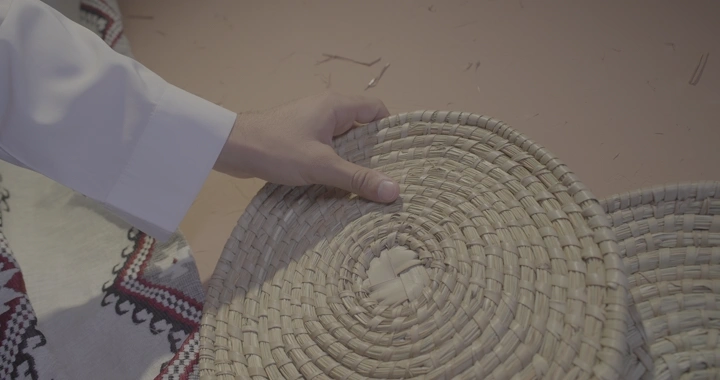 يد تمسك بساط تقليدي في مكان تراثي، لقطة مقربة.