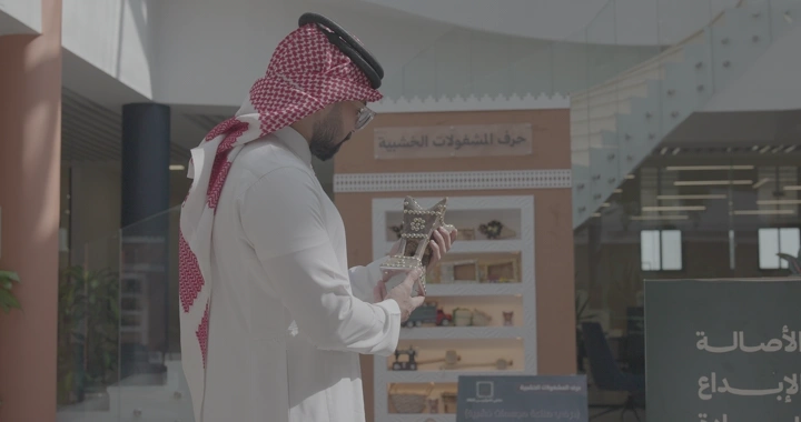 رجل يرتدي الزي التقليدي يحمل مدخنة مصنوعة بشكل يدوية في معرض داخلي، لقطة جانبية.