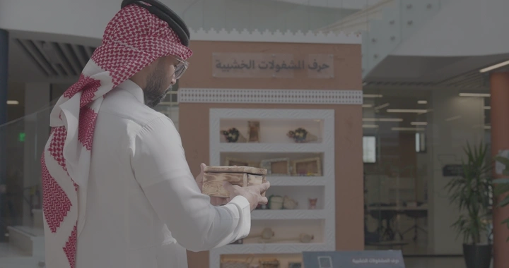 رجل يحمل صندوق مصنوع يدوياً خشبي في معرض للحرف اليدوية، لقطة داخلية.