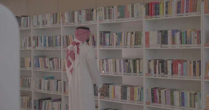 رجل يختار كتابًا من مكتبة حديثة، لقطة جانبية.