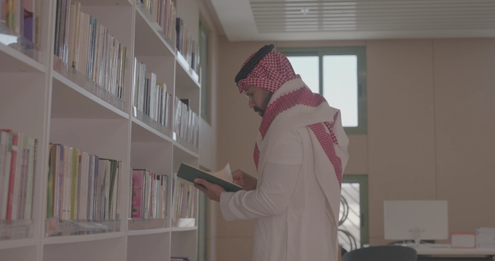 شخص يقرأ في مكتبة حديثة، لقطة جانبية.