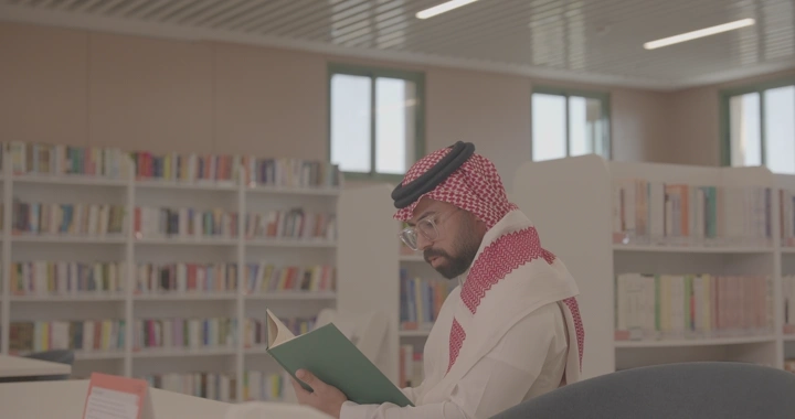 رجل يقرأ في مكتبة حديثة، لقطة داخلية.