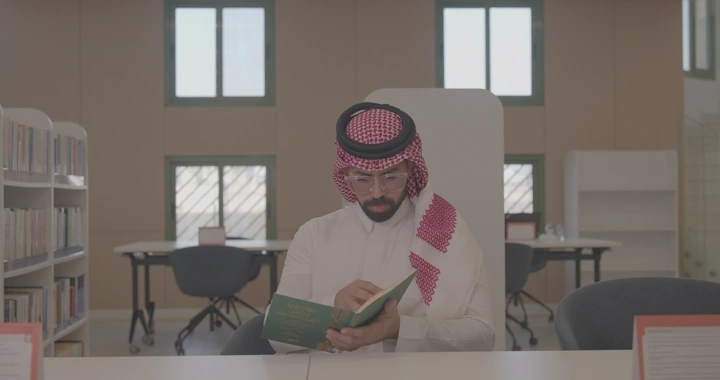 رجل يقرأ في مكتبة مضيئة، لقطة داخلية.