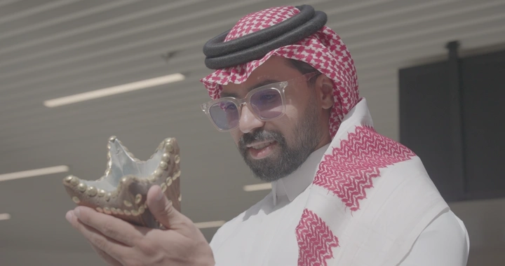 رجل يرتدي الزي التقليدي يتأمل مدخنة يدوية، لقطة مقربة.