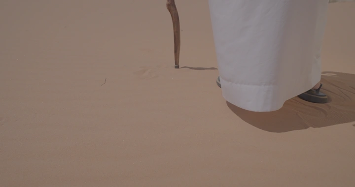 رجل يمشي على رمال الصحراء في النهار، لقطة قريبة.