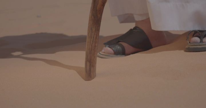 رجل يضرب العصا في رمال النفود، لقطة قريبة.