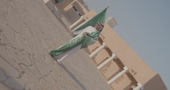 رجل يحمل العلم السعودي في قصر القشلة بحائل ، لقطة واسعة.