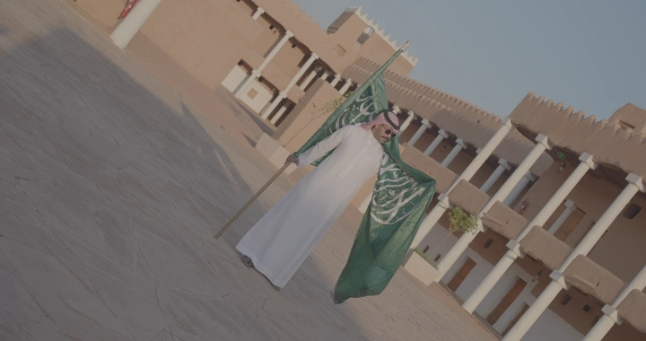 رجل يحمل العلم السعودي في قصر القشلة بحائل، لقطة واسعة.