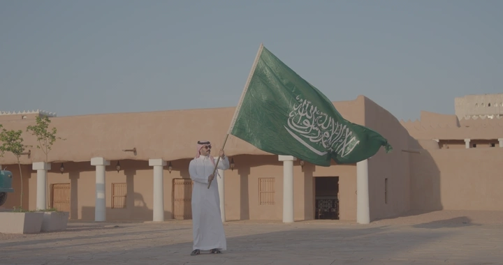 رجل يحمل العلم السعودي في قصر القشلة بحائل، لقطة نهارية.