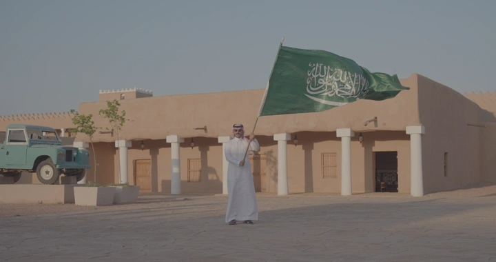 رجل يحمل العلم السعودي في قصر القشلة بحائل، لقطة نهارية.