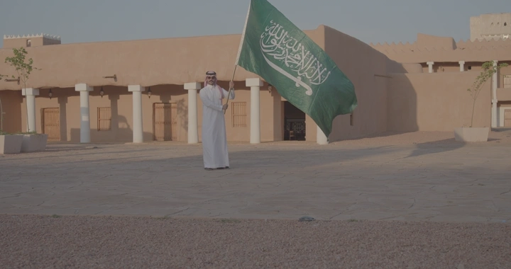 رجل يحمل العلم السعودي في قصر القشلة بحائل، لقطة نهارية.