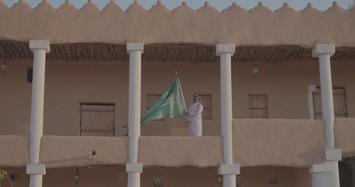 رجل يحمل العلم السعودي في قصر القشلة بحائل، لقطة نهارية.