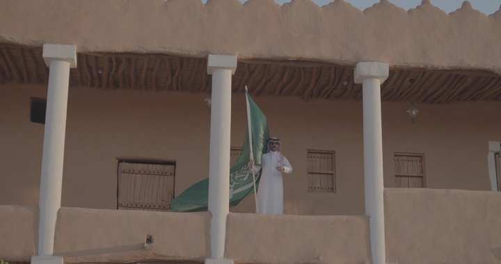 رجل يحمل العلم السعودي في قصر القشلة بحائل، لقطة نهارية.