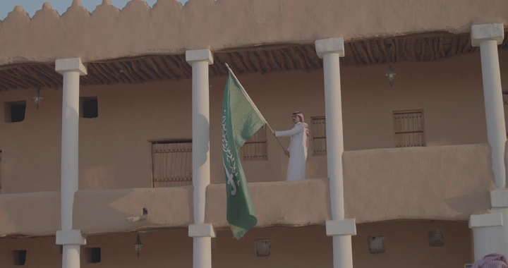 رجل يحمل العلم السعودي في قصر القشلة بحائل، لقطة نهارية.