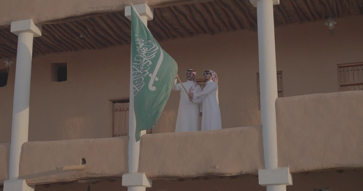 رجلان يحملان العلم السعودي في قصر القشلة بحائل، لقطة نهارية.