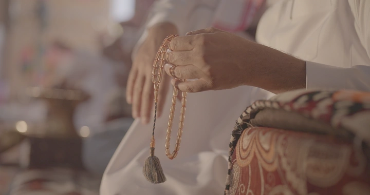 شخص يحمل سبحة في مجلس عربي، لقطة قريبة.