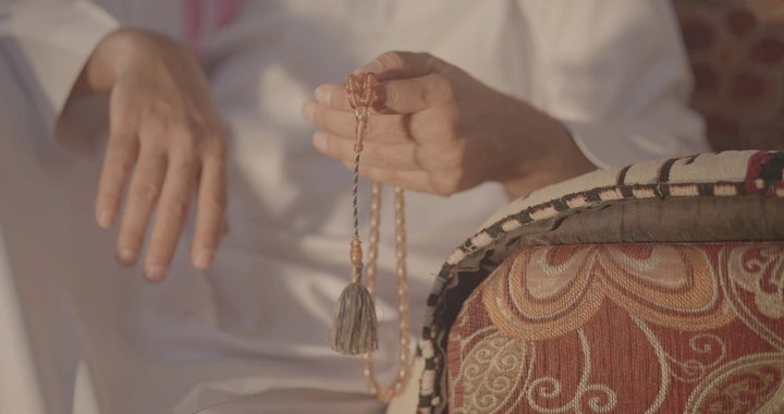 يد تحمل سبحة في ضوء الشمس، لقطة مقربة.